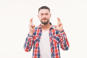 Naklejka premium Young man praying with finger crossed gesture looking up isolated on white