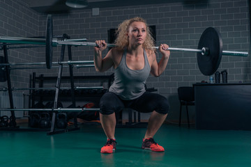 Fototapeta na wymiar Powerful woman athlete doing squats with heavy weights. cross-training