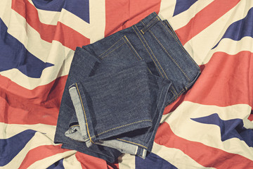 Blue Jeans Denim, 100% Cotton Unsanforized Denim Red Selvage Jeans on The Flag of England vintage tone color style background, selective focus (detailed close-up shot)
