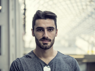 Obraz premium Handsome young man profile shot, indoor, inside big modern building, maybe a brand new train station, looking at camera smiling