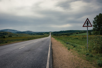 Asphalt road to the horizon line under a cloudy sky.
