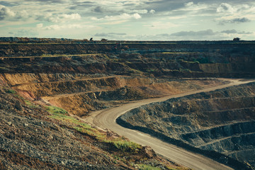 Landscape of the deep quarry with working machinery. Extraction of raw materials.