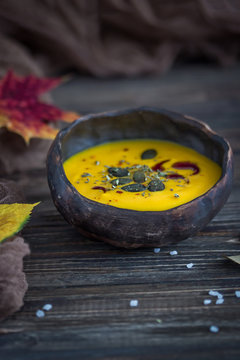 Vegetarian pumpkin cream soup with pumpkin seeds and pumpkin oil on a dark background