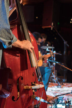 Acoustic Trio Band Performing On A Stage In A Nightclub, With The Double Bass Player In Focus