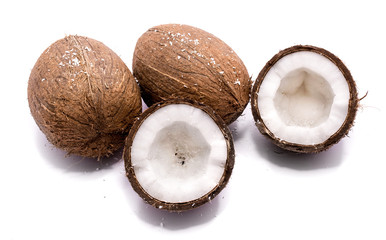 Two whole coconuts and two cracked coconut halves with shavings isolated on white background