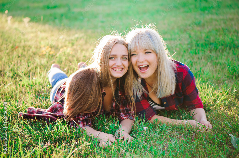 Wall mural two happy female friends playing and having fun in green grass