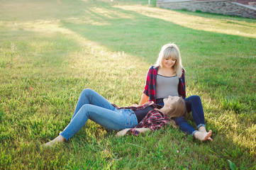 Fototapeta premium Two happy female friends playing and having fun in green grass