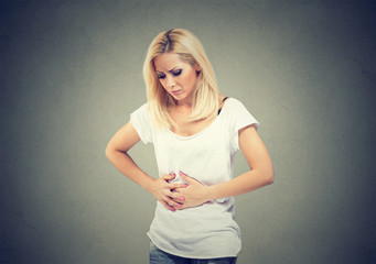 Young woman hands on stomach having bad aches pain. Food poisoning and cramps. Negative emotion...
