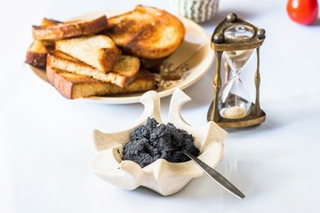 Black caviar, fried bread and sandglass.
