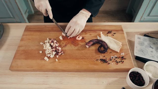 Cook hands is slicing of boiled squid. One of the stages of cooking calamaries. seafood restaurant top view