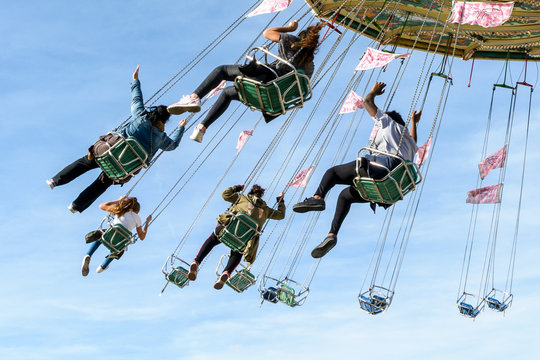 A rotating chair swing ride carousel with teenagers enjoying the ride in a parisian amusement park.