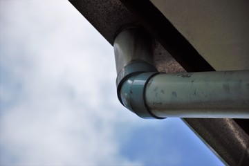 Fototapeta premium Corner of the house with gutters on a background of blue sky.