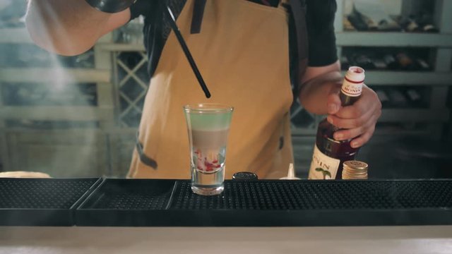 bartender prepares B52 Shot, cocktail preparation in modern bar with fire, tequilla vodka rum gin