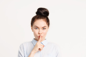 Fototapeta premium Brunette girl with long hair holds finger near lips . the gesture of silence, mystery, mystery