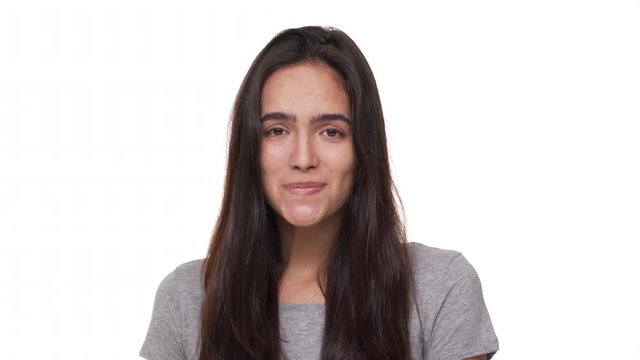 portrait of shy caucasian woman with pursed lips smiling at camera hesitating feeling embarrassed isolated over white background closeup. Concept of emotions