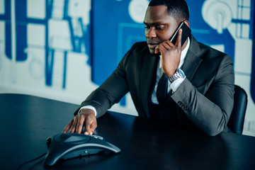 Attractive Afro-American young businessman on conference ip phone in office