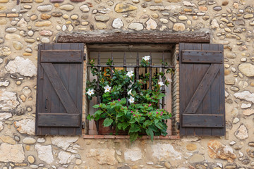 Window in an old house decorated with flower pots and flowers