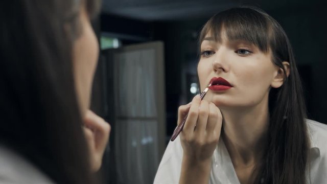 Beautiful attractive woman make up herself in front of the mirror get ready for photoshot and wink her eye to camera