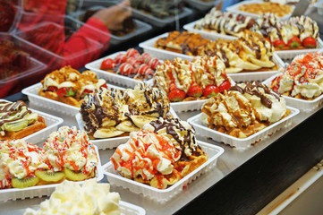 The Belgian wafer. Delicious Belgian waffle with cream, fruit and sauce looks beautiful in the window of the Brussels confectionery store.