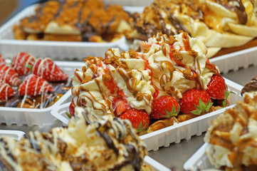 The Belgian wafer. Delicious Belgian waffle with cream, fruit and sauce looks beautiful in the window of the Brussels confectionery store.