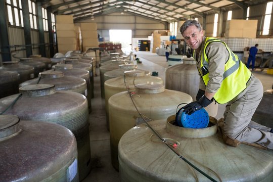 Portrait Of Happy Worker Removing Oil From Tank