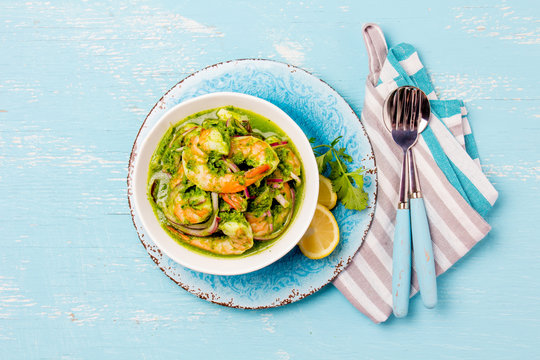 MEXICAN CUISINE. Aguachile de camaron. Prawns aguachile. Shrimps eviche cebiche with cucumber, lemon and purple onion. Top view, blue background
