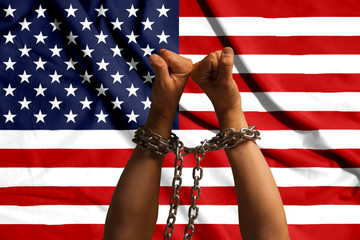 Two hands shackled a metal chain on the background of the USA flag