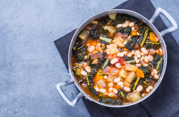 Soup with beans, kale top view text space.