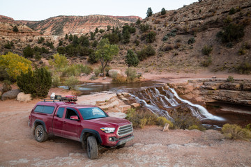 Red pickup camping rig on rocky trail near waterfall in southern Utah © DCrane Photography