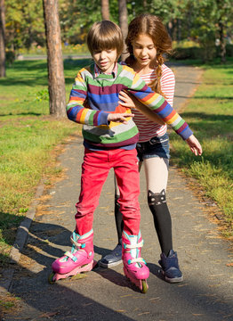 The girl helps the boy to roller-skate.