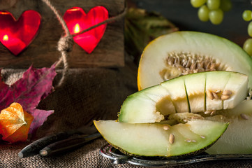 Large juicy chunks of ripe melon on the background of beautiful candles and bunches of grapes. Close-up.