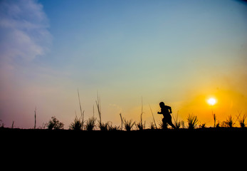 Boy walking on the meadow at sunset