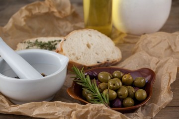 Mortar pestle by olives in plate on paper