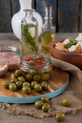Close up of green olives by containers on cutting board