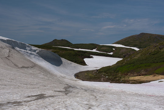 Bright white glacier on the slopes of mount Kurodake with a river running underneath, Daisetsuzan National Park, Hokkaido, Japan