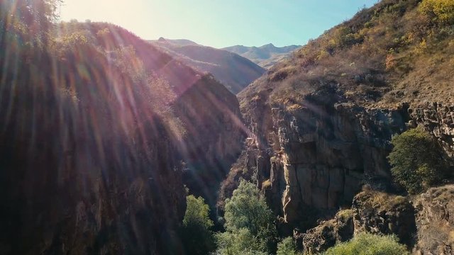 4K aerial shot mountain gorge and cliff with sun leaks