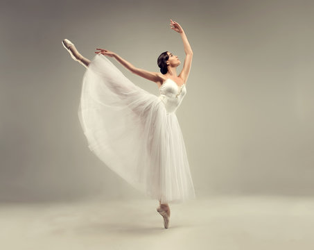 Fototapeta Ballerina. Young graceful woman ballet dancer, dressed in professional outfit, shoes and white weightless skirt is demonstrating dancing skill. Beauty of classic ballet.
