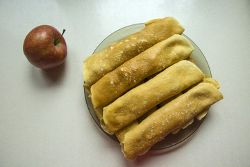 Pancakes on a plate and one apple