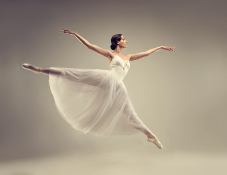 Fototapeta Ballerina. Young graceful woman ballet dancer, dressed in professional outfit, shoes and white weightless skirt is demonstrating dancing skill. Beauty of classic ballet.