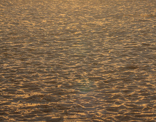 The sand on the beach gilded by the sunset