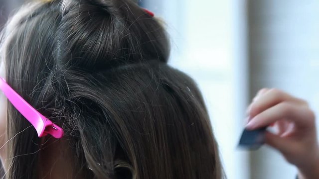Hairdresser backcombing womans hair.Beauty salon