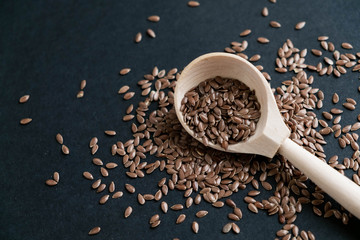 Flax seeds in spoons over dark background. Natural light. Selective focus. Close up on a black background. Top view, flat lay. copy space