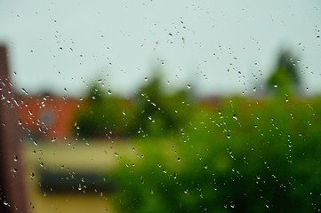 Fototapeta Krople deszczu na szybie, w tle dachy i budynki. obraz