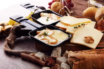  Delicious traditional Swiss melted raclette cheese on diced boiled or baked potato served in individual skillets © beats_