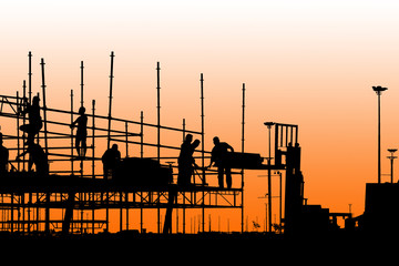 Silhouette of construction workers working on scaffolding with twilight sky