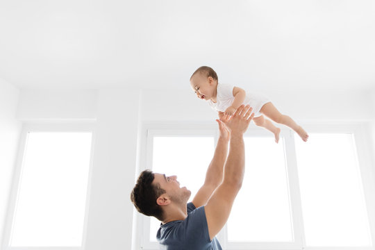 Young father throwing baby in the air