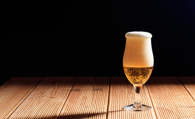 A glass of beer on a wooden table, dark background