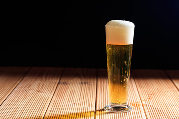 A glass of beer on a wooden table, dark background