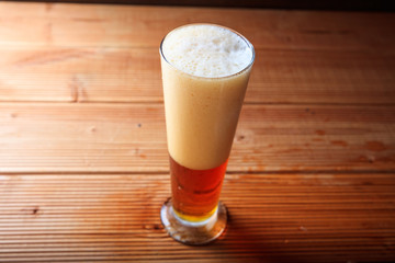 A glass of red beer on a wooden table