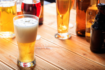 A wooden pub counter, focus on a full frosty glass of beer